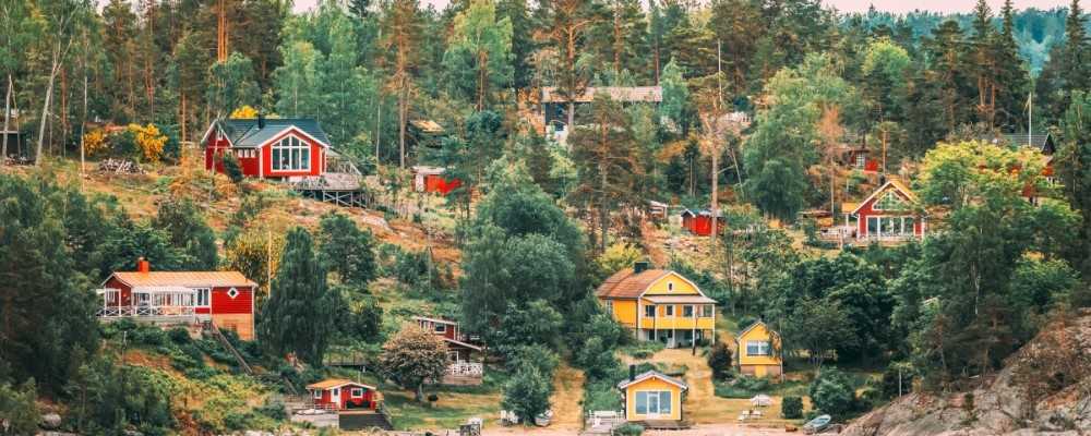 Sweden. Many Beautiful Red And Yellow Swedish Wooden Log Cabins Houses On Rocky Island Coast In