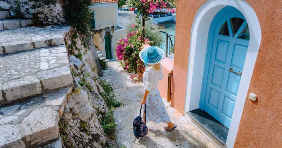Travel tourist woman walking through narrow streets of an old greek town 